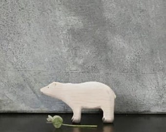 May include: A white wooden polar bear toy, standing on a gray background. The bear is facing left and has a simple, stylized design.