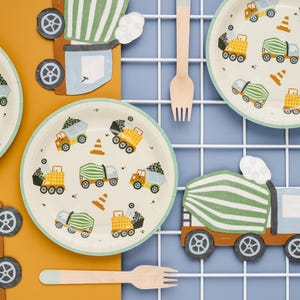 May include: Construction-themed party supplies, including plates, forks, and truck-shaped decorations. The plates feature illustrations of dump trucks, cement mixers, and traffic cones. The color palette includes beige, orange, green, and blue.