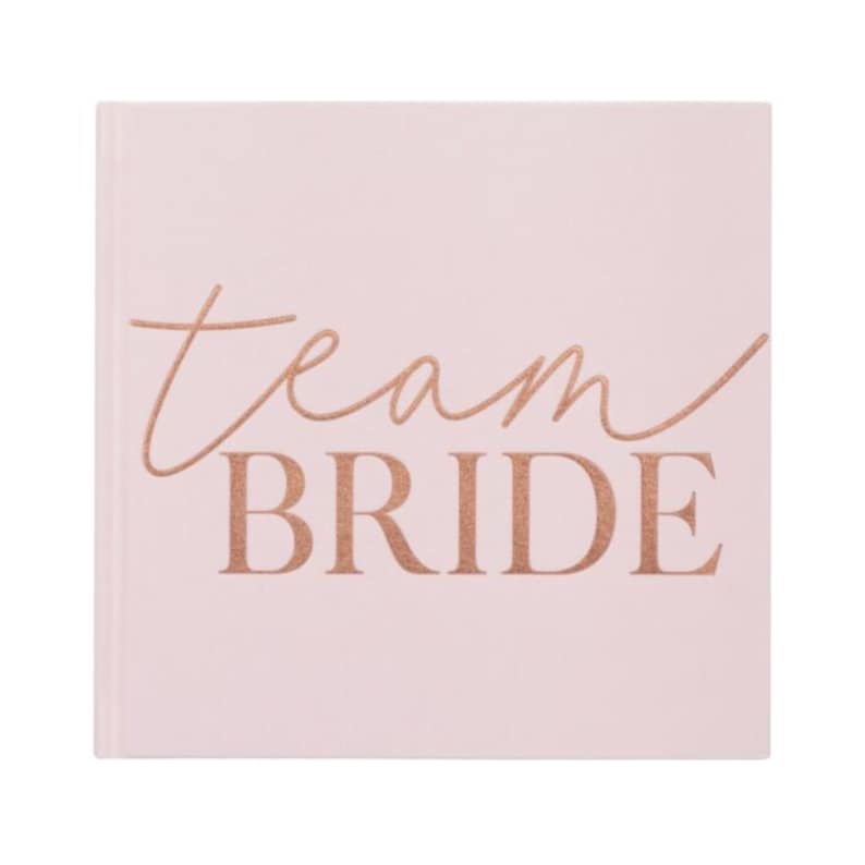 Op de afbeelding: Een roze vierkant notitieboekje met de tekst "Team Bride" in ros&eacute;goud.