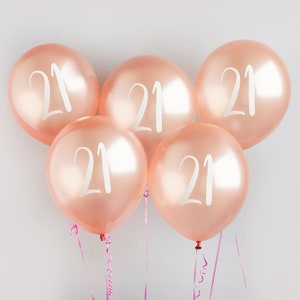 以下が含まれることがあります： 5つの桃色の風船に、それぞれ白い文字で「21」と印刷されています。