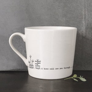 May include: White ceramic mug with a black line drawing of three potted plants and the text "A brew will see you through..."