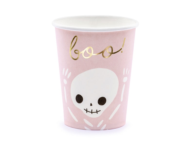 May include: A pink paper cup with a white interior and a gold "boo!" script. The cup features a white skeleton design with black eyes and a smiling mouth, perfect for Halloween parties.
