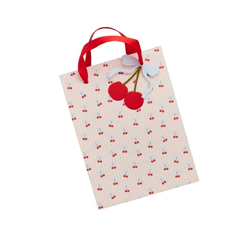 May include: A rectangular gift bag with a light pink and white vertical striped pattern featuring small red cherry illustrations. The bag has red ribbon handles and a decorative cutout of two red cherries with a light blue bow attached to the top.