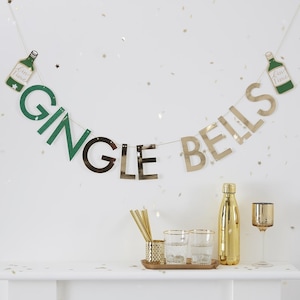 May include: A gold and green banner with the words "Gingle Bells" and two green bottles with the text "Gin Time" hanging on a white wall. The banner is decorated with gold glitter stars.