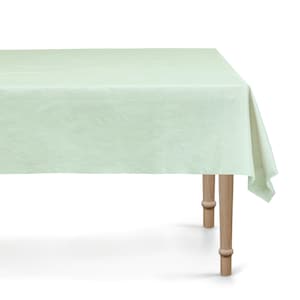 Op de afbeelding: Een lichtgroen rechthoekig tafelkleed op een houten tafel. Het tafelkleed heeft een textuur en hangt over de randen van de tafel. De tafel heeft vier houten poten.