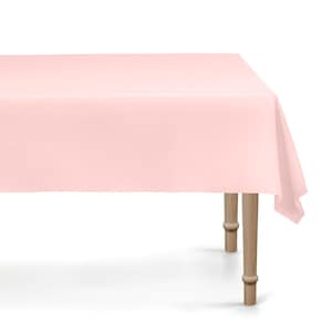 Peut inclure: Une nappe rectangulaire rose clair sur une table en bois. La nappe est en tissu lisse et recouvre la table, avec un coin qui pend du bord. La table a quatre pieds en bois.