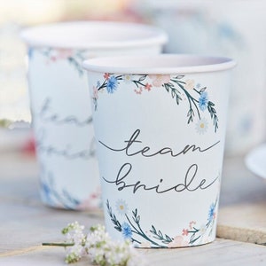 May include: White paper cups with a floral design and the text "team bride" printed on them.