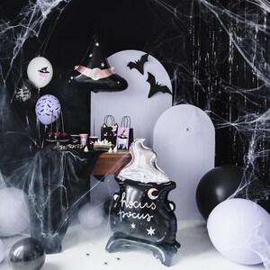 May include: A black cauldron balloon with the text "Hocus Pocus" and a crescent moon. The balloon is surrounded by white, black, and purple balloons, a witch hat balloon, and black bats. The background is a black and white spiderweb.