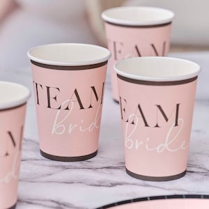 May include: Pink paper cups with black trim and the text "Team Bride" in black and white lettering.