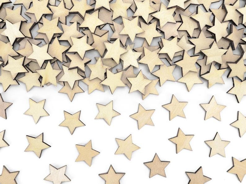 May include: A pile of wooden stars in a light brown colour, scattered on a white background. The stars are arranged in a random pattern, with some overlapping.