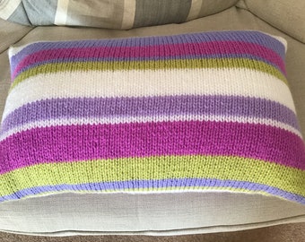 Könnte beinhalten: Ein gestreiftes, gestricktes Kissen mit weißen, lila, rosa und grünen Streifen.