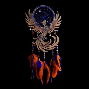 Handcrafted phoenix-shaped dreamcatcher with a deep blue woven web, orange and blue feathers, star beads, and crystal drops. Symbolizes rebirth and strength. Perfect for fantasy-themed or boho-style home decor.