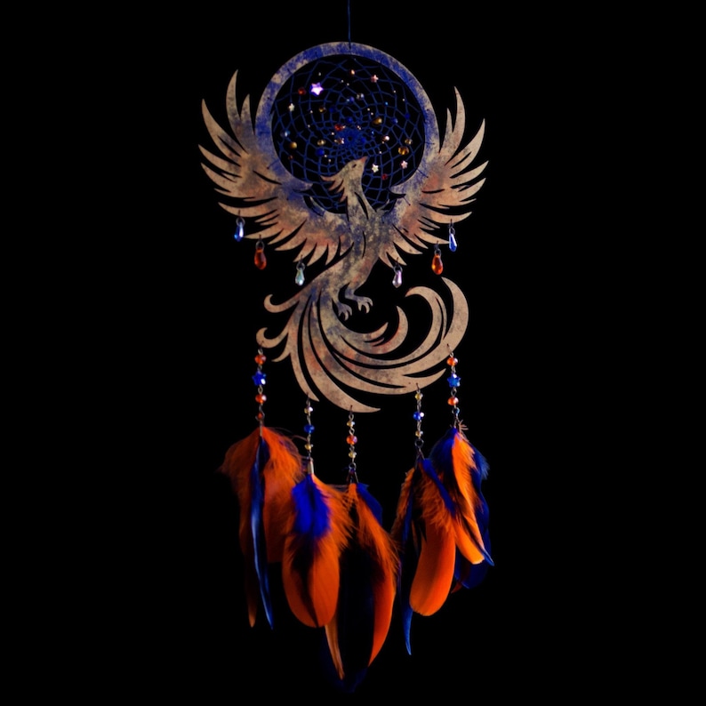 Handcrafted phoenix-shaped dreamcatcher with a deep blue woven web, orange and blue feathers, star beads, and crystal drops. Symbolizes rebirth and strength. Perfect for fantasy-themed or boho-style home decor.