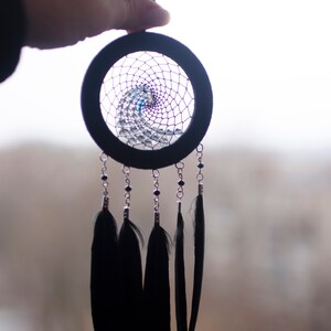 May include: A black dreamcatcher with a beaded web and black feathers hanging from it.