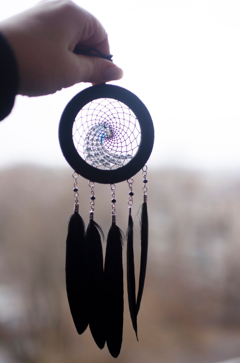 May include: A black dreamcatcher with a beaded web and black feathers hanging from it.
