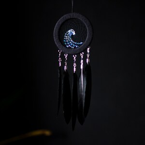 May include: A black dreamcatcher with a blue and white beaded wave design and black feathers hanging from it.