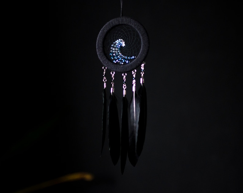May include: A black dreamcatcher with a blue and white beaded wave design and black feathers hanging from it.