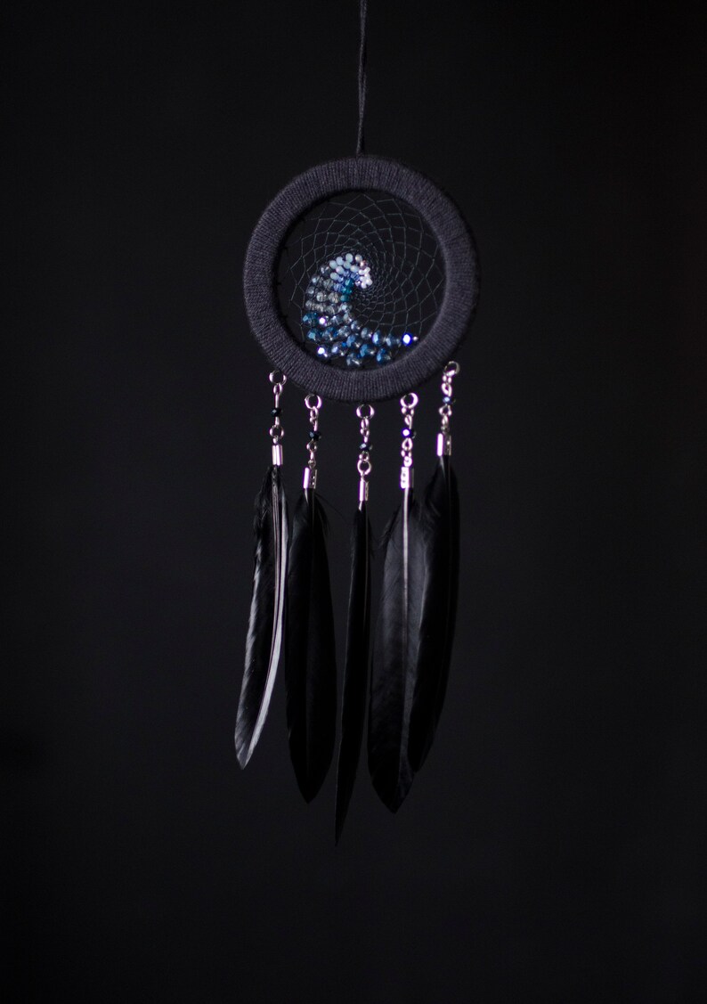 May include: A black dreamcatcher with a blue and white beaded wave design and black feathers hanging from the bottom.