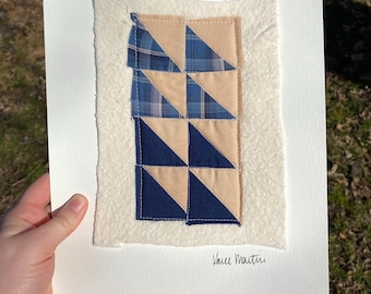 May include: A framed piece of art featuring a patchwork quilt with blue and beige triangles. The quilt is signed "Vance Martin".