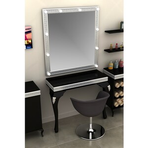 May include: A black vanity table with a silver trim and a large mirror with lights around the frame. The table has a black chair with a silver base.