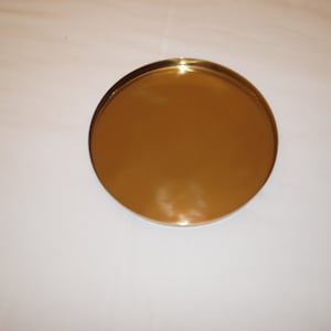 Pu&ograve; includere: Un vassoio rotondo in metallo color oro.