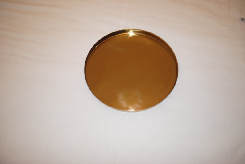 Pu&ograve; includere: Un vassoio rotondo in metallo color oro.