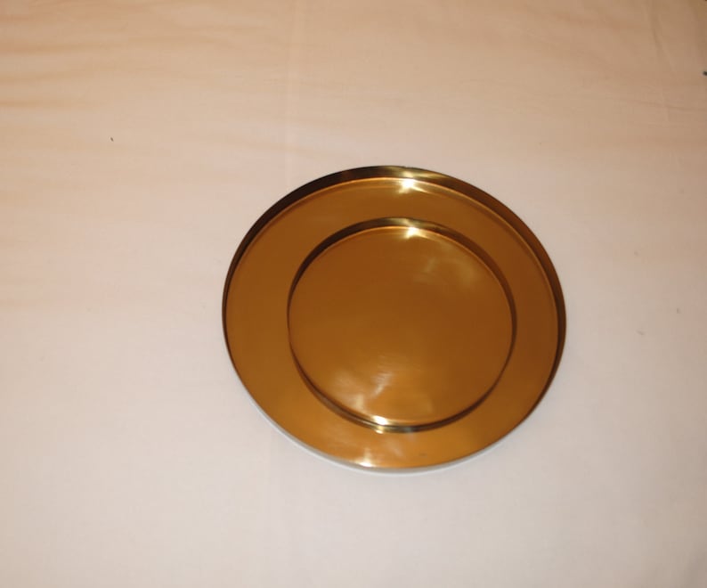 Pu&ograve; includere: Due piatti rotondi in metallo color oro, uno leggermente pi&ugrave; piccolo dell'altro, sono impilati uno sopra l'altro.