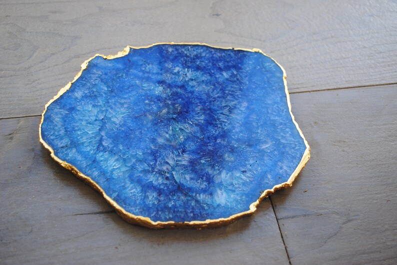Puede incluir: Un posavasos de &aacute;gata azul con borde dorado. El posavasos tiene una forma natural e irregular y una superficie pulida. El color azul var&iacute;a en tonalidad, creando un patr&oacute;n &uacute;nico. Este art&iacute;culo decorativo es adecuado para la decoraci&oacute;n del hogar.
