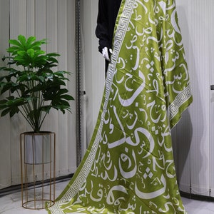 May include: A set of five silk scarves featuring a white Arabic calligraphy design on a green, blue, red, brown, and black background. The scarves have a white and green geometric border.