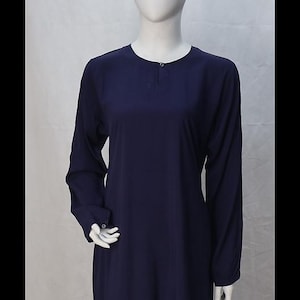 May include: A long, navy blue dress with long sleeves and a buttoned neckline. The dress is displayed on a mannequin against a white backdrop. The dress has a simple, elegant design.