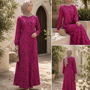 May include: A long-sleeved, floor-length magenta dress featuring a black floral pattern, a round neckline, and a small gold-toned button detail at the collar. The dress is paired with a solid beige headscarf and a small, structured beige handbag.