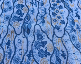 Könnte beinhalten: Blauer und goldener Stoff mit einem sich wiederholenden Muster aus stilisierten Blumen und Blättern. Der Stoff hat eine strukturierte Oberfläche.