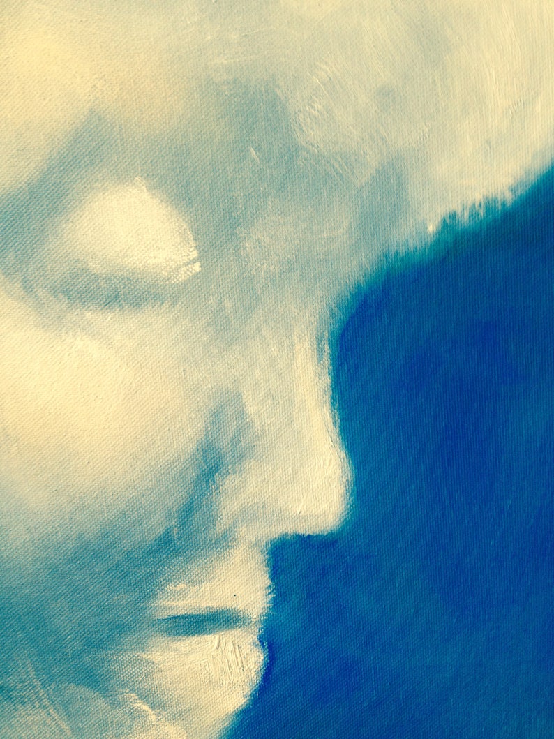 May include: A close-up of a painting depicting a face in profile, with the left side of the face painted in a light beige color and the right side of the face painted in a dark blue color.