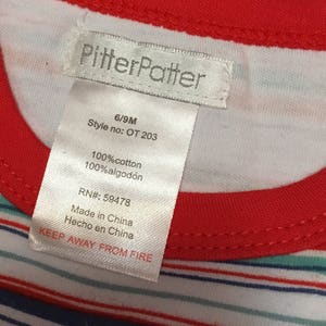 May include: White and red striped shirt with a white tag that says "PitterPatter" and includes details like size, style number, fabric content, RN number, and "Keep Away From Fire".