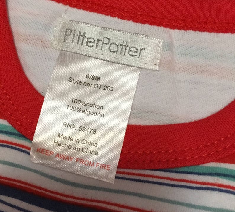 May include: White and red striped shirt with a white tag that says "PitterPatter" and includes details like size, style number, fabric content, RN number, and "Keep Away From Fire".