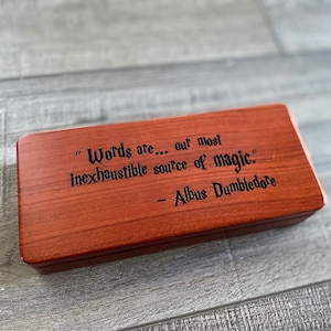 May include: A wooden box with a quote from Albus Dumbledore engraved on the top: "Words are... our most inexhaustible source of magic." - Albus Dumbledore