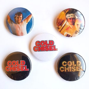 May include: Five round button pins with a black and white image of a man with a headband and the text "COLD CHISEL" in red letters on a white background, and two black button pins with the text "COLD CHISEL" in gold letters on a black background.