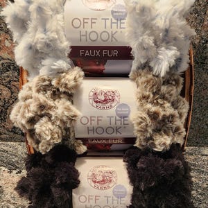 May include: A basket filled with three different colors of Lion Brand Off The Hook Faux Fur yarn. The colors are white with blue, brown with tan, and black. The packaging reads "No tools needed!"
