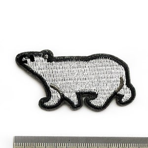 Puede incluir: Un parche bordado de un oso polar blanco con contornos negros. El parche mide aproximadamente 3 cm de ancho y 2 cm de alto.