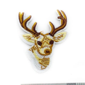 Puede incluir: Parche bordado con la cabeza de un ciervo, con costuras detalladas en marrón, dorado y blanco. El parche mide unos 7,6 cm de alto y está sobre un fondo blanco. Este parche es un artículo decorativo.