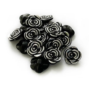 May include: A pile of black and silver rose-shaped buttons.