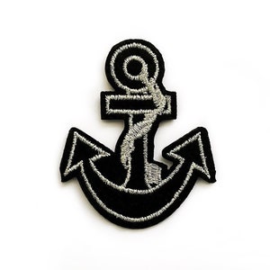 Könnte beinhalten: Ein schwarzer Anker-Stickerei-Aufnäher mit silbernem Umriss. Der Aufnäher ist etwa 5 cm breit und 6,5 cm hoch.
