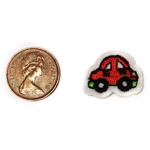 May include: A red embroidered iron-on patch of a car with black wheels and green headlights. The patch is about the size of a US penny.