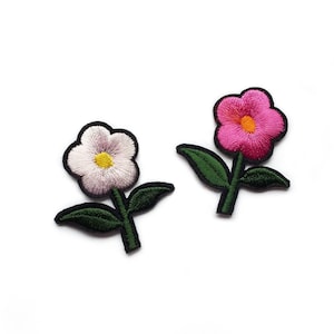 May include: Two embroidered iron-on patches of flowers. One flower is pink with a yellow centre and the other is white with a yellow centre. Both flowers have green stems and leaves.