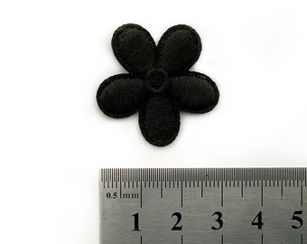 May include: A black embroidered flower patch, approximately 2 cm in diameter, with five petals. The patch is shown next to a ruler for size reference.