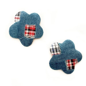 Peut inclure: Deux écussons en forme de fleur en denim avec des accents en tissu à carreaux. Chaque écusson a une base en denim bleu avec des écussons en tissu à carreaux rouges, noirs et blancs. Sur fond blanc.
