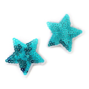 May include: Two turquoise blue star-shaped patches made of sequins. The stars are on a white background.