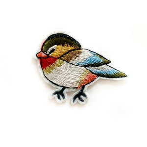 May include: Embroidered iron-on patch of a small bird with a brown head, white body, red breast, and blue and green wings.
