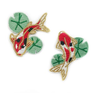 Könnte beinhalten: Zwei gestickte Bügelbilder mit roten und weißen Koi-Karpfen, die über grünen Seerosen schwimmen.