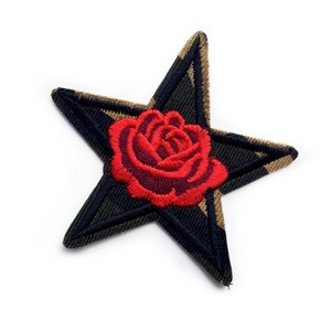 May include: Embroidered star-shaped patch featuring a red rose at the center. The star has a black and olive green camouflage pattern with a black border. This decorative patch can be ironed on or sewn onto clothing or accessories.